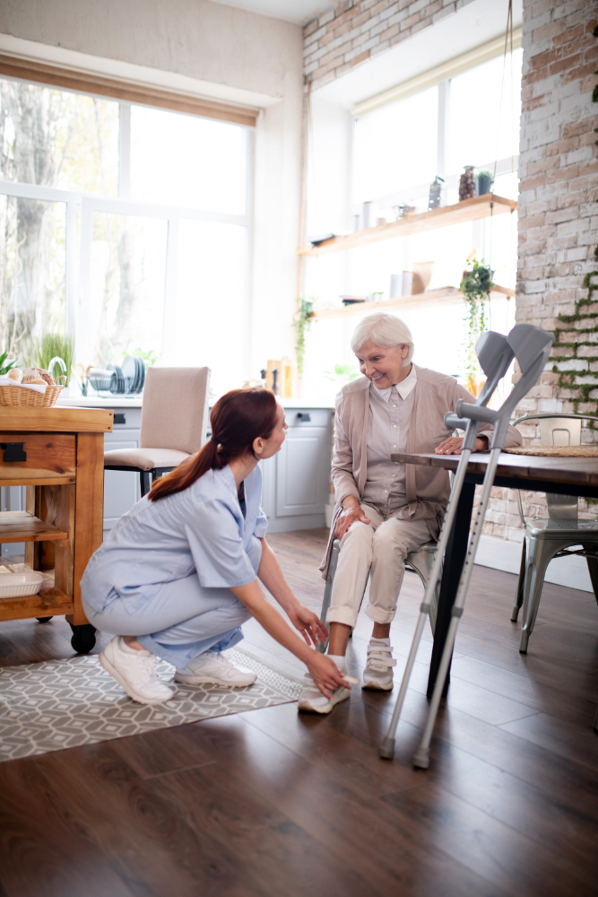 pensioner-smiling-while-caregiver-lacing-shoes-her